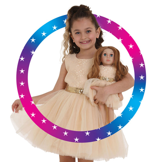 Girl wearing Cream Dress with sparkling gold belt holding Mais, the Little Me Doll, also wearing a matching Cream Dress with sparkling belt, facing forward