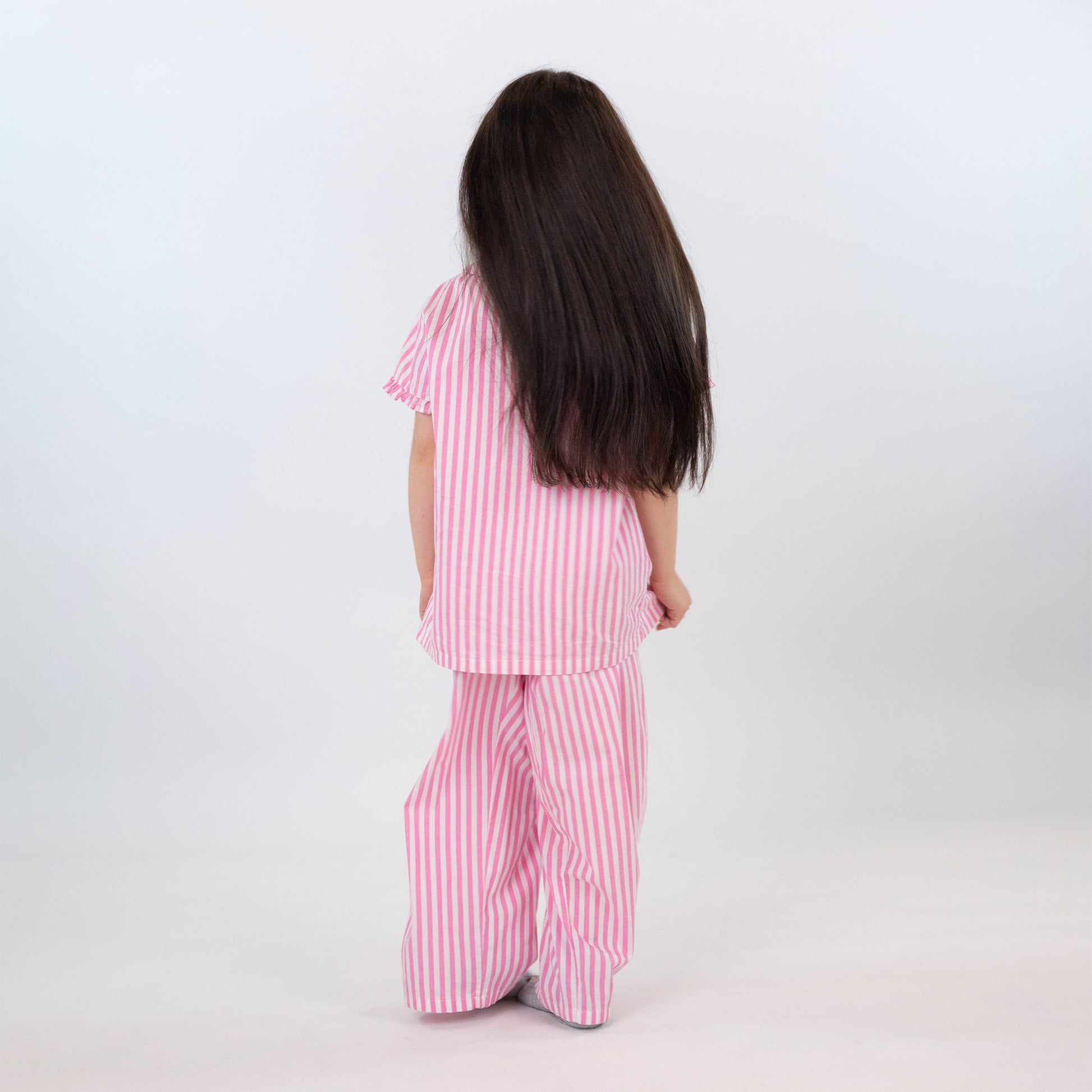 Girl facing backwards wearing long pink and white stripped long pajamas by laftakids