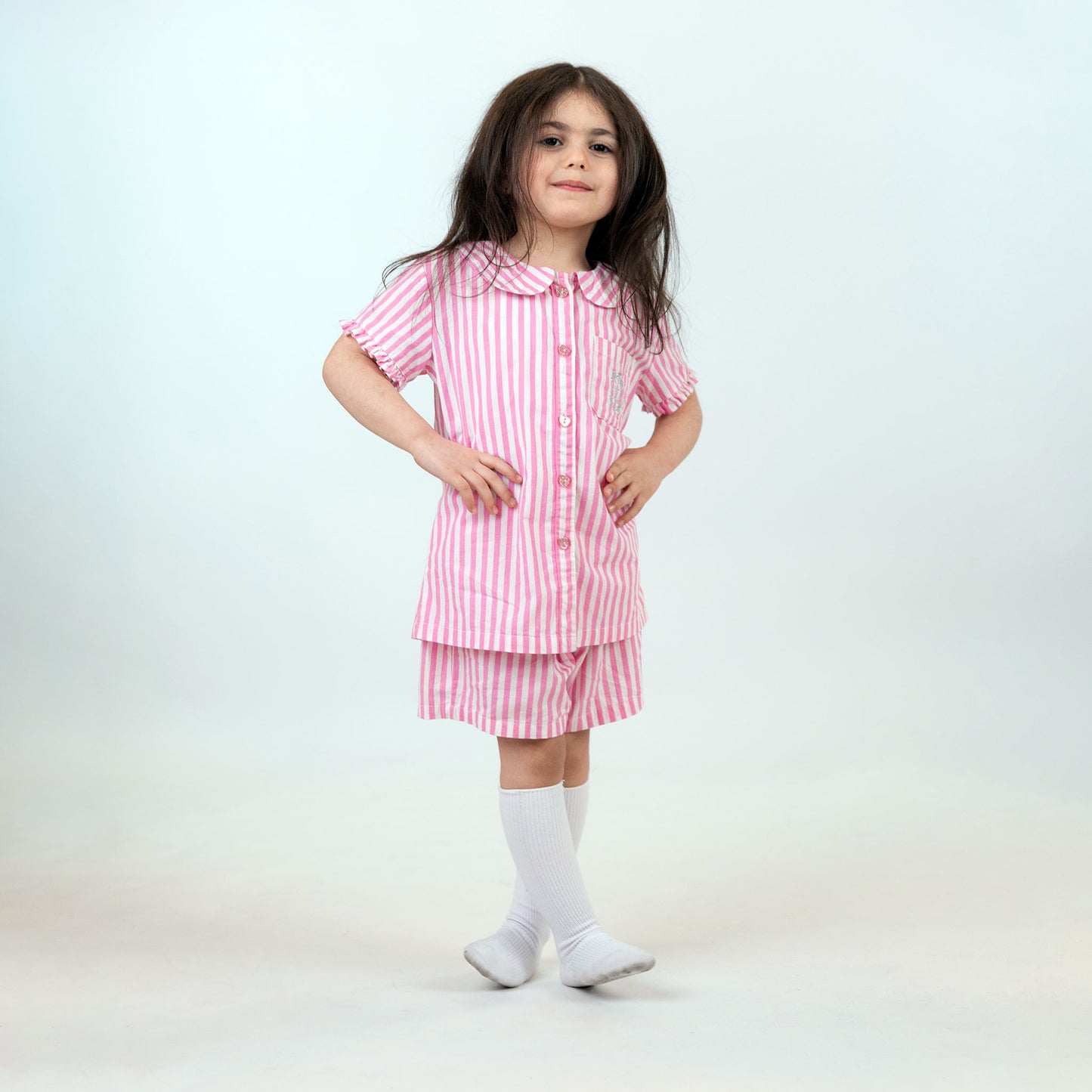 Girl wearing LaftaKids pink and white short pajama, facing forward